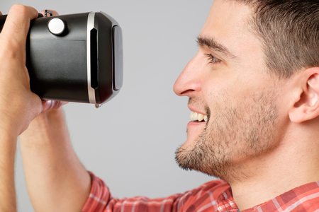 Attractive man using virtual reality headset isolated on a gray backgroundの写真素材