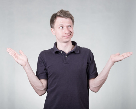 Doubtful young man on grey backgroundの写真素材