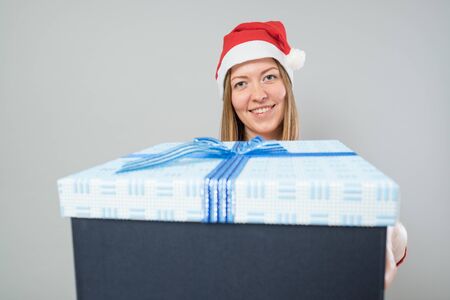 Young woman happy smile hold gift box in hands, isolated over greyの写真素材