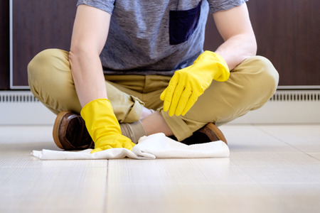 Man's hands manually cleaning the floor with white ragの写真素材