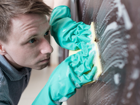 Man cleaning kitchen furniture by yellow clothの写真素材