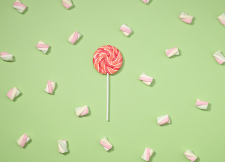Sweet marshmallows minimalism set with red lollipop on pastel apple green backgroundの写真素材