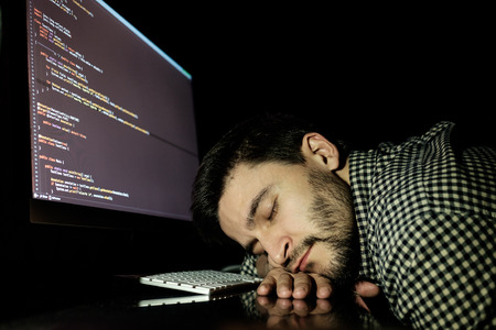 Freelancer programmer falling his face down taking a nap with computer. Concept of tired and lazyの写真素材