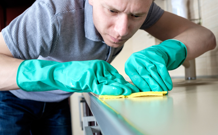 Man cleaning kitchen furniture by yellow cloth