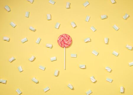 Sweet marshmallows minimalism set with red lollipop on pastel straw yellow backgroundの写真素材