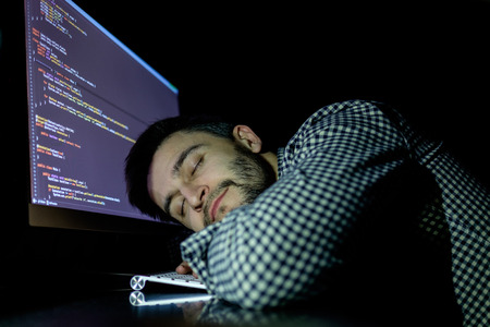 Freelancer programmer falling his face down taking a nap with computer. Concept of tired and lazyの写真素材