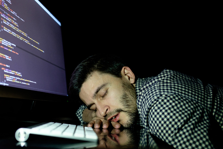 Freelancer programmer falling his face down taking a nap with computer. Concept of tired and lazyの写真素材