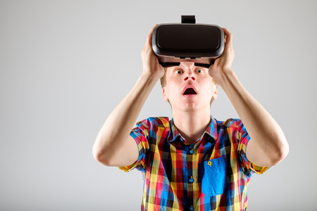 Handsome man wearing virtual reality glasses isolated on a gray backgroundの写真素材