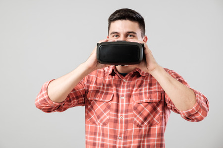 Attractive man using virtual reality headset isolated on a gray backgroundの写真素材