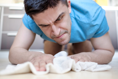 Man in blue tee manually mopping the tile floor in his houseの写真素材