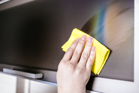 Man's hand holding a yellow rag and cleaning furniture in the kitchenの写真素材