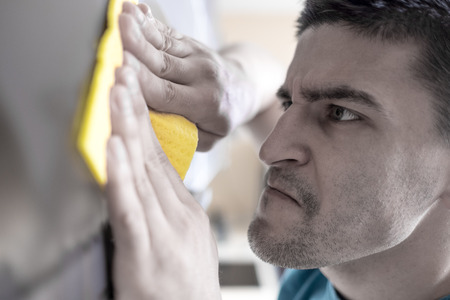 Man cleaning kitchen furniture by yellow clothの写真素材