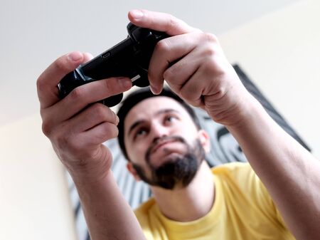 Addiction. Bearded man playing video game by controller. Face expression.の写真素材