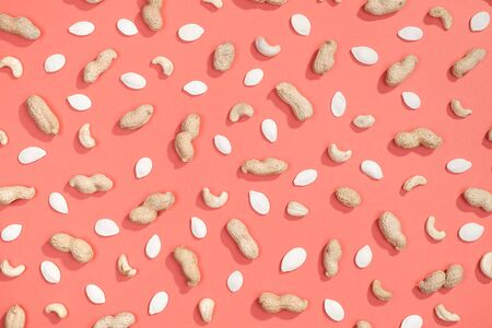 Peanut, pumpkin seeds and cashews flat lay pattern on red backgroundの写真素材