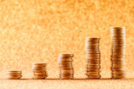 Stacks of copper coins arranged as a graph on golden glitter background. Financial conceptの写真素材