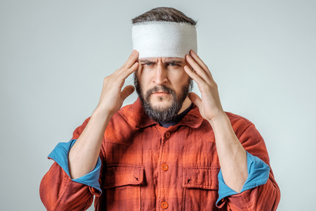 Portrait of man with bandages wrapped around his head isolated on gray backgroundの写真素材
