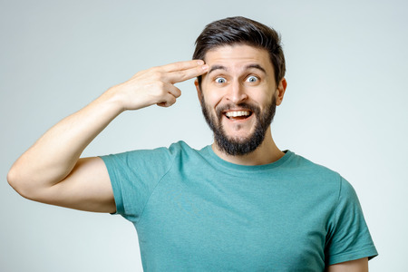 Depressed young man shooting to his head isolated on grayの写真素材