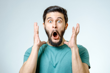 Man with shocked, amazed expression isolated on gray backgroundの写真素材