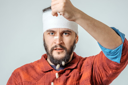 Sad injured bandaged man with pills over gray background