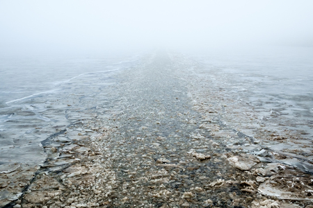 Channel made by an icebreaker on a river with a fog in perspective