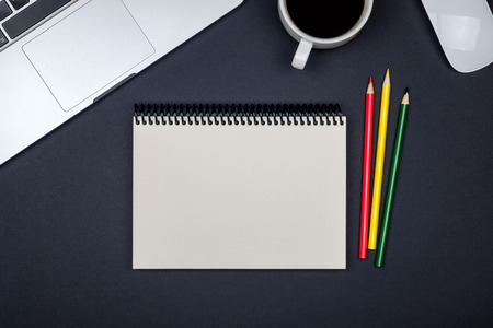 Modern black office desk table with laptop and blank notebook page for input the text. Top view, flat layの写真素材