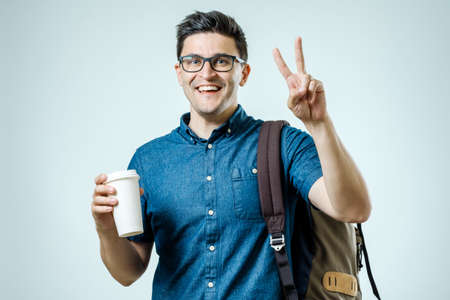 Portrait of young man with backpack isolated on gray background