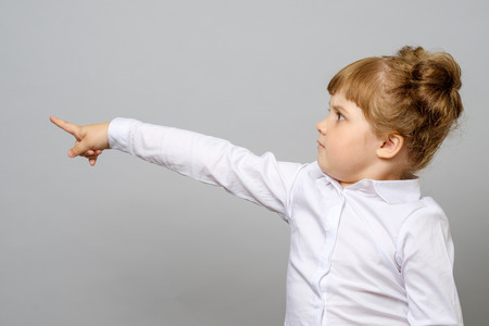 Cheerful little girl pointing away isolatedの写真素材