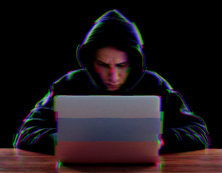 Hacker in a dark hoody with Russian flag using laptop. Cybersecurity concept. Glitch effect added