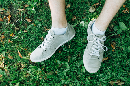 Male feet in gray gumshoes on green grass