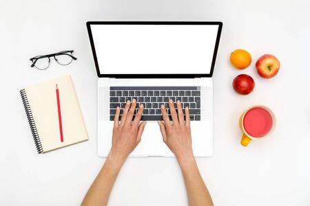 Home office workspace mockup. Laptop with blank screen, hands and accessories on white background. Flat lay. Top viewの写真素材