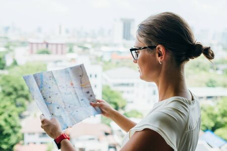 Back side of traveler girl searching right direction on map, traveling along Asia. Freedom and...