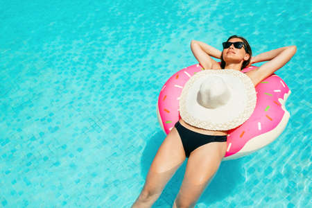 Summer Vacation. Enjoying suntan woman in bikini on the inflatable mattress in the swimming poolの写真素材
