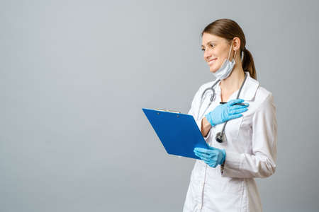 Young doctor woman against gray background happy, smiling and cheerfulの写真素材