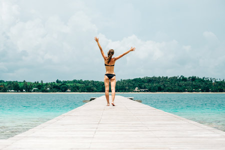 Woman in bikini walking down a tropical jettyの写真素材