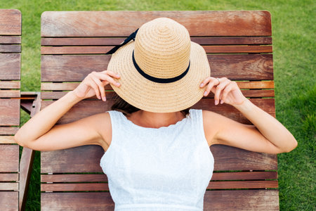 Beautiful young woman lies and rests on a deckchairの写真素材