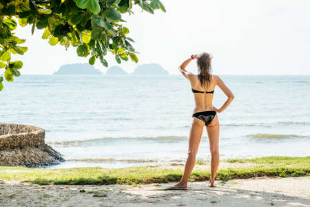 Happy woman enjoying beach in summer. Beautiful bikini model relaxing on travelの写真素材