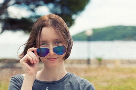 Portrait of young woman in sun glasses, with blurred sea landscape behind  Textured の写真素材