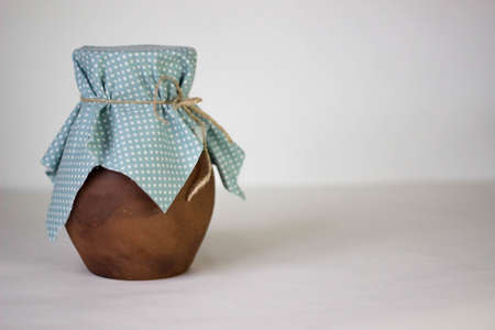 Brown clay jug with blue cloth on a white backgroundの写真素材