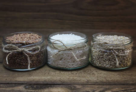 Three small glass transparent jars with cerealsの写真素材