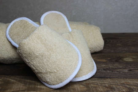 Terry cloth towel and bath slippers on a wooden board.の写真素材