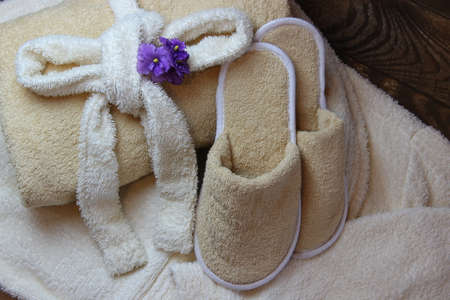 Terry cloth towel and bath slippers lying on a dressing gown.の写真素材