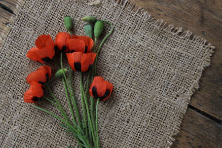 The flowers of red poppy on a linen cloth and wooden boardsの写真素材