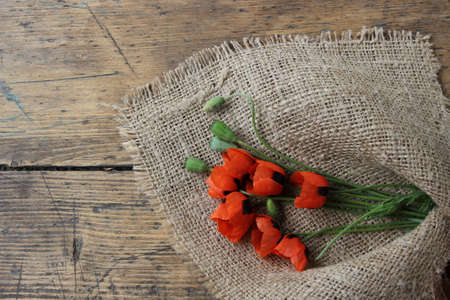 The flowers of red poppy on a linen cloth and wooden boardsの写真素材