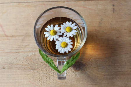Glass of chamomile tea on wooden boardsの写真素材