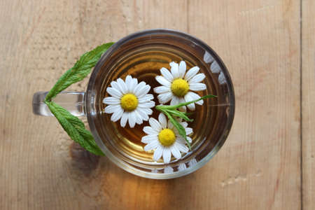 Glass of chamomile tea on wooden boardsの写真素材