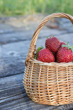 Red ripe strawberries in a wicker basket on the background of wooden boardsの写真素材