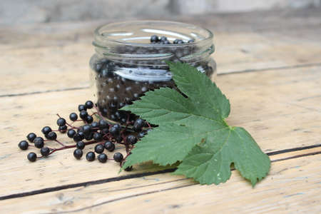 Ripe elderberry fruits in a glass jar