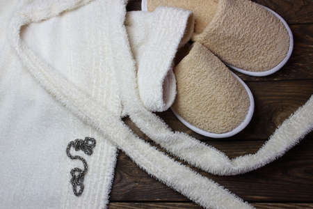 Terry bathrobe and bath slippers on wooden boardsの写真素材
