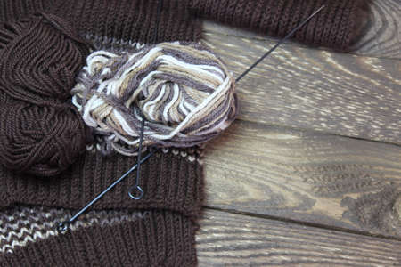 Tangle of thread and knitting needles against the background of boards