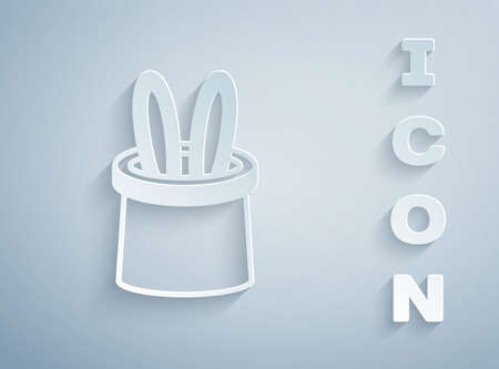 Paper cut Magician hat and rabbit ears icon isolated on grey background. Magic trick. Mystery entertainment concept. Paper art style. Vectorのイラスト素材